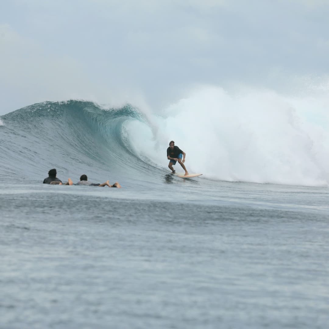 Sylvain en surf devant une vague qui déferle
