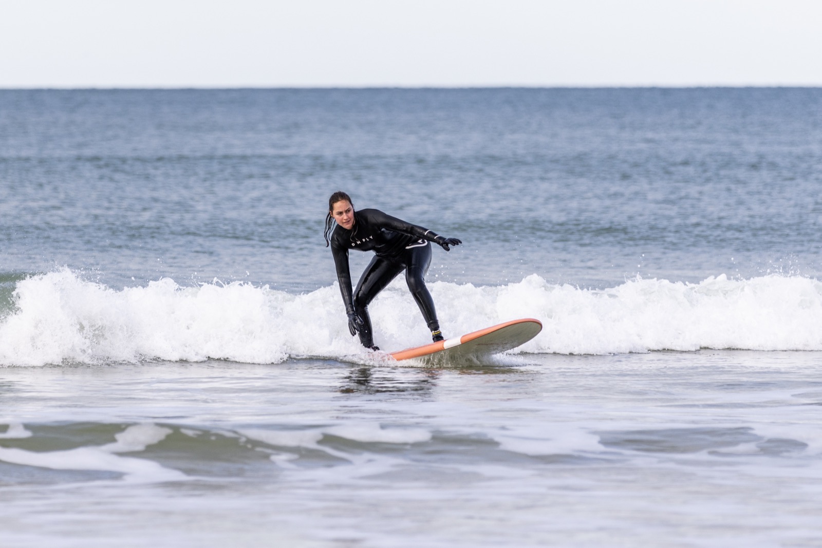 Une élève debout sur sa planche dans la mousse