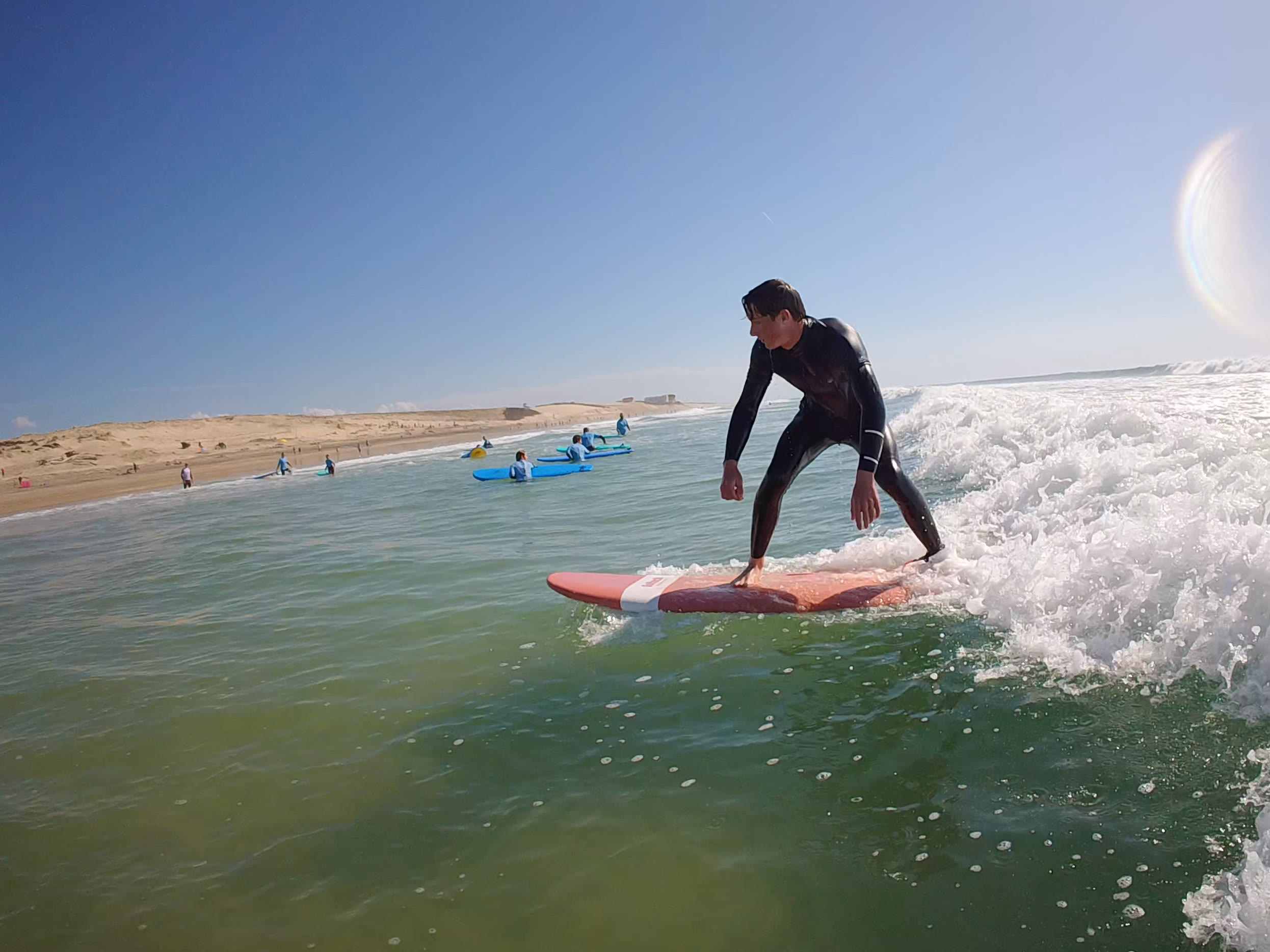 Un élève debout sur sa planche dans la mousse, filmé à la GoPro