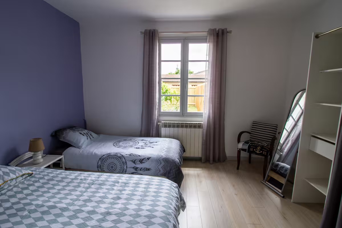 Chambre au mur mauve avec deux lits simples